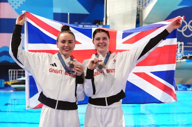 Spendolini-Sirieix and Toulson celebrating, holding their bronze medals in front of them and a Union Flag behind them. 