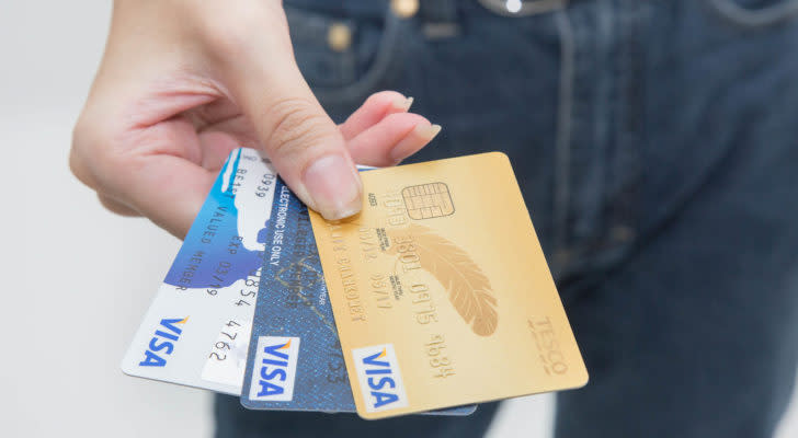 An outstretched hand holds three different Visa credit cards.