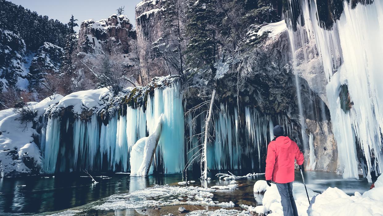  Man standing in front of frozen waterfall, Hanging lake, Colorado. 
