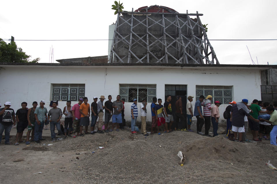 Migrants line up to receive food handouts in front of the backside of a church heavily damaged in a Sept. 7, 2017 earthquake, as a thousands-strong caravan of Central Americans hoping to reach the U.S. border stops for the night in Niltepec, Oaxaca state, Mexico, Monday, Oct. 29, 2018. As the caravan resumed its slow advance Monday, still at least 1000 miles or farther from the U.S., the Pentagon announced it would send 5,200 active-duty troops to "harden" the border. (AP Photo/Rebecca Blackwell)