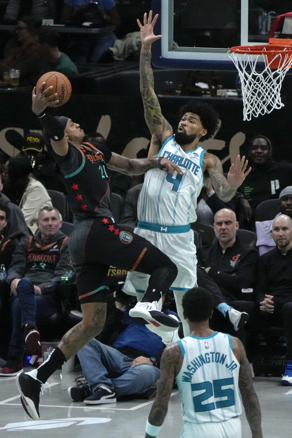 Washington Wizards forward John Butler Jr., left, drives to the basket against Charlotte Hornets center Nick Richards, top right, during the first half of an NBA basketball game Friday, Nov. 10, 2023, in Washington. (AP Photo/Mark Schiefelbein)