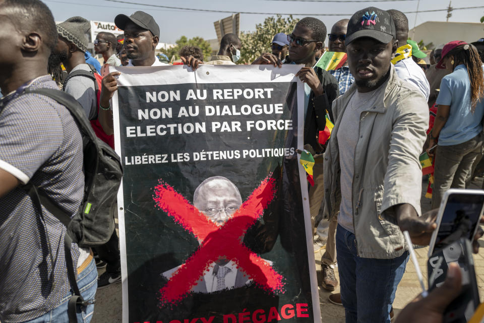Supporters of the Aar Sunu Senegal opposition collective display a banner reading - 'No to postponement, no to dialogue, election by force', on a street, in Dakar, Saturday, Feb. 17, 2024. Senegal's government says it will hold a presidential election as soon as possible given that the country's top election authority has overturned a decree by President Macky Sall to postpone the vote. (AP Photo/Sylvain Cherkaoui)