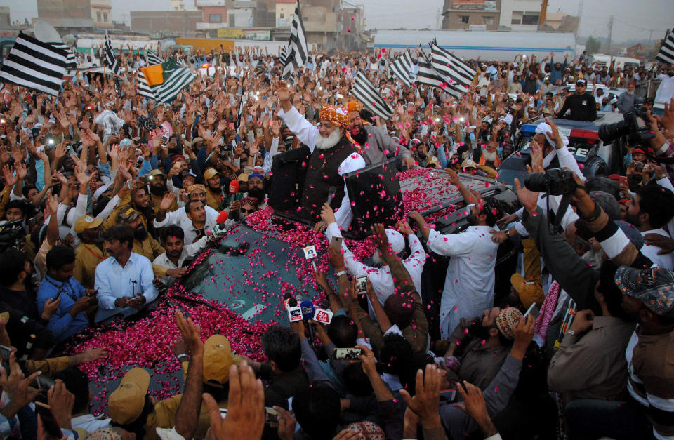 Maulana Fazlur Rehman, center, head of the Jamiat Ulema-e-Islam party, is greeted by supporters with rose-petals during an anti-government march as it arrives in Hyderabad, Pakistan, Sunday, Oct. 27, 2019. Thousands of supporters of the ultra-religious party are marching to Islamabad, Pakistan's capital. (AP Photo/Pervez Masih)
