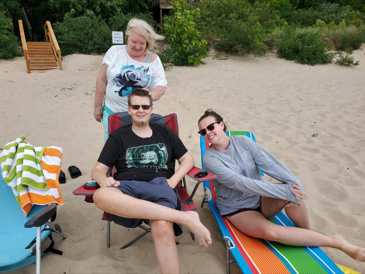 Devin Loudy, 19, sits on a beach chair near the shores of Lake Michigan while his grandmother, Laura Loudy, and girlfriend, Mia Patterson, sit beside him. Doctors diagnosed Devin Loudy with a glioblastoma brain tumor in 2016. The vacation was paid for by Physicians for Wishes, created by Muncie physician Dr. Gregory Taylor.