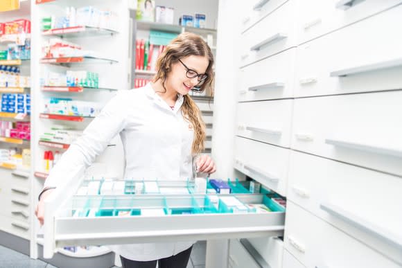 Woman in lab coat looking at medications in a drawer