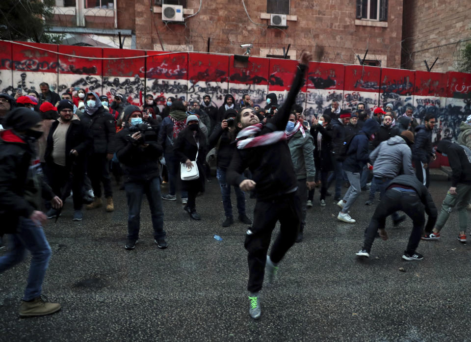 Anti-government protesters throw stones towards the central bank building during a demonstration to denounce the country's deteriorating economic and financial conditions, in front of the Central Bank in Beirut, Lebanon, Sunday, Jan. 23, 2022. (AP Photo/Bilal Hussein)