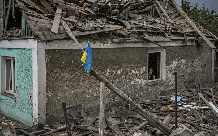 A Ukrainian flag is placed in front of a destroyed house after a strike in the city of Dobropillia in the eastern Ukrainian region of Donbas & nbsp;  - ARIS MESSINIS / AFP