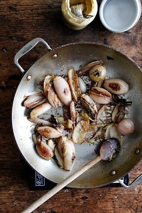 Sautéed squid with garlic on a stovetop pan, wooden handle, next to condiments