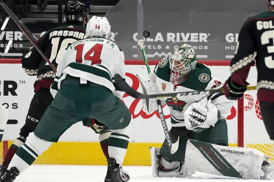 Minnesota Wild goaltender Cam Talbot, right, has a shot go off his stick as Arizona Coyotes center Derick Brassard (16) and Wild center Joel Eriksson Ek (14) look on during the second period of an NHL hockey game Wednesday, April 21, 2021, in Glendale, Ariz. (AP Photo/Ross D. Franklin)