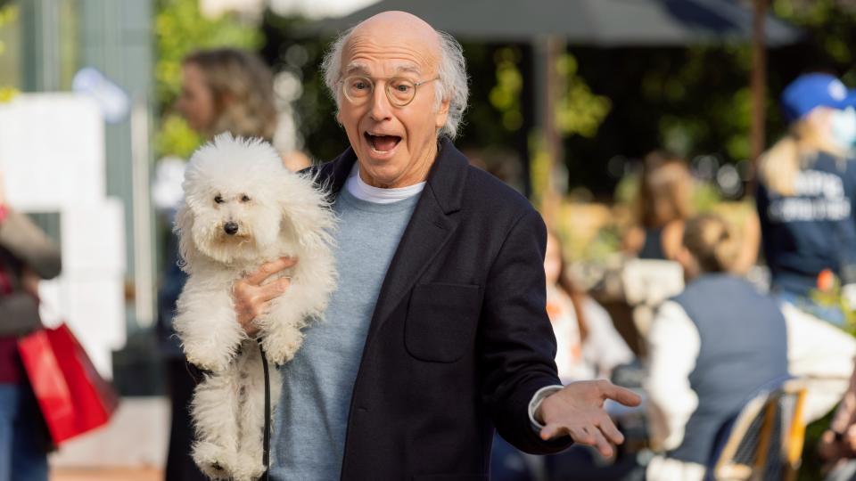 Curb Your Enthusiasm's Larry David smiling holding a dog