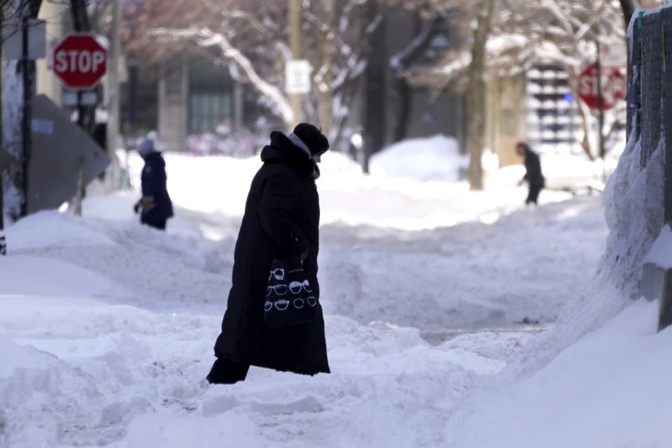 People navigate snowy streets and sidewalks the morning after a snowstorm in the Chicago area, Tuesday, Feb. 16, 2021. There have been record subzero temperatures in Texas and Oklahoma, and Greenland is warmer than normal. Snow fell in Greece and Turkey. Meteorologists blame the all-too-familiar polar vortex. (AP Photo/Charles Rex Arbogast)