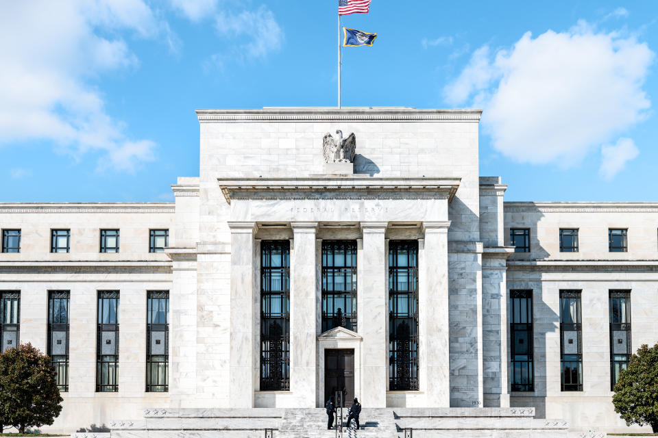 Washington DC, USA - March 9, 2018: Federal Reserve bank entrance, facade architecture building, wall security guards standing by doors, path, American flags, blue sky