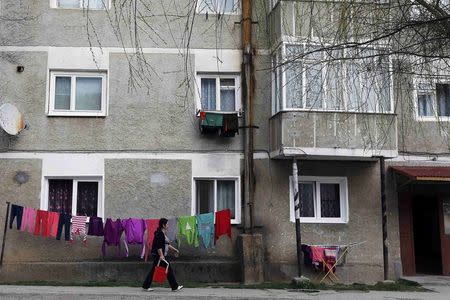 A woman walks in front of a building in Abrud, central Romania March 24, 2014. REUTERS/Bogdan Cristel