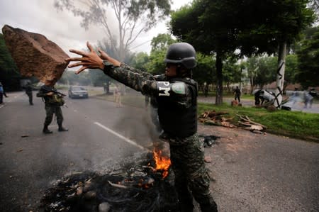 A member of the military police removes rocks from a barricade during a protest against the government of Honduras' President Juan Orlando Hernandez, in Tegucigalpa