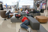 In this Monday, May 5, 2014 photo, passengers sleep on new couches in the Tom Bradley International Terminal at Los Angeles International Airport (LAX). TBIT is a completed part of improvements at the aging airport, which is scheduled to get newly surfaced roads, upgraded restaurants with Los Angeles themes, and some terminal makeovers that will infuse more sunlight into otherwise cave-like interiors. Also in the plans are new bathrooms and, that essential for travelers, more outlets and USB ports for charging electronic devices. (AP Photo/Nick Ut )