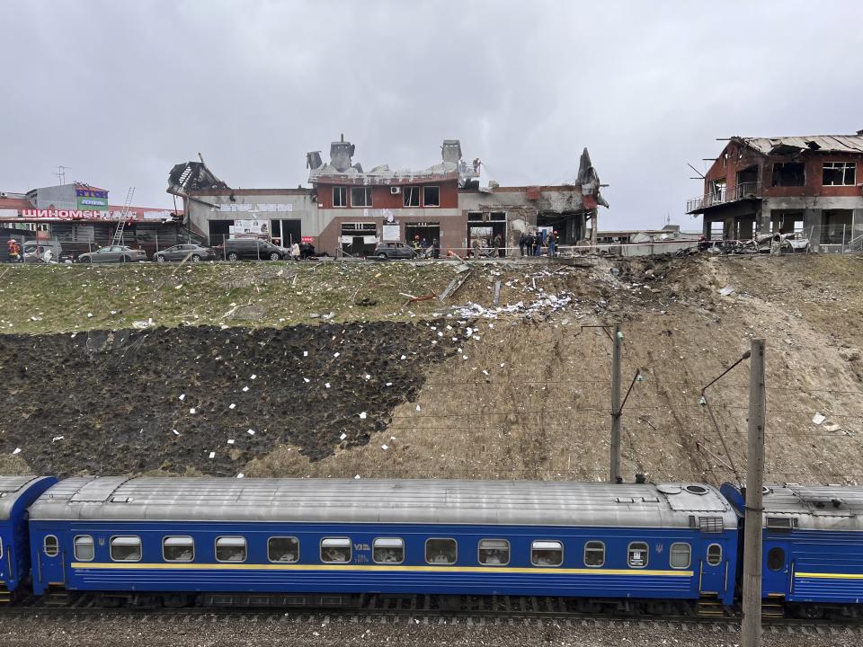 A train travelling from Dnipro passes by the area where emergency workers clear up debris after an airstrike hit a tire shop in the western city of Lviv, Ukraine, Monday April 18, 2022. Russian missiles hit the city of Lviv in western Ukraine on Monday, killing at least six people, Ukrainian officials said, as Moscow’s troops stepped up strikes on infrastructure in preparation for an all-out assault on the east. (AP Photo/Philip Crowther)