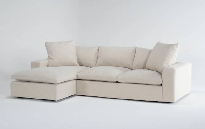 A modern beige sectional sofa with an L-shaped design and four detachable cushions. No people or additional objects are present