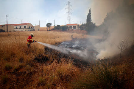 A firefighter helps to put out a fire in Pinheiro e Garrado, near Silves, Portugal August 8, 2018. REUTERS/Pedro Nunes