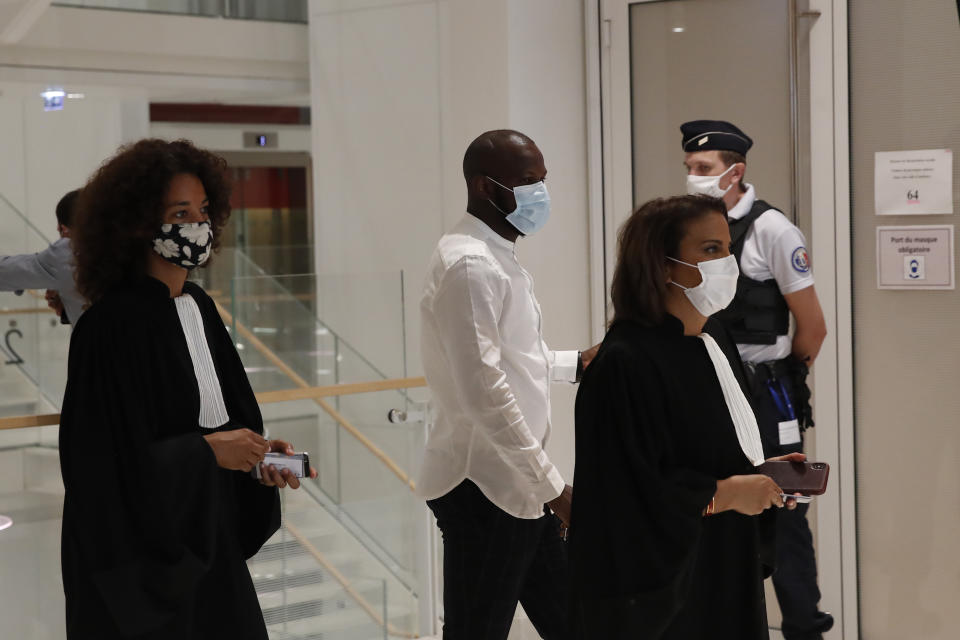 Lassana Bathily, center, who saved lives during the attack of a kosher supermarket in 2015, arrives at the courtroom before the 2015 attacks trial, Wednesday, Sept. 2, 2020 in Paris. Thirteen men and a woman go on trial Wednesday over the 2015 attacks against a satirical newspaper and a kosher supermarket in Paris that marked the beginning of a wave of violence by the Islamic State group in Europe. Seventeen people and all three gunmen died during the three days of attacks in January 2015. (AP Photo/Francois Mori)