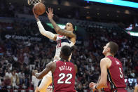 Washington Wizards forward Kyle Kuzma goes to the basket past Miami Heat forward Jimmy Butler (22) and forward Nikola Jovic during the first half of an NBA basketball game, Sunday, March 10, 2024, in Miami. (AP Photo/Lynne Sladky)