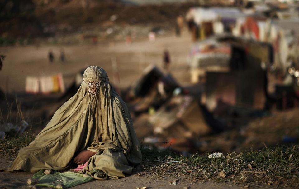 In this Monday, March 4, 2013 photo, a Pakistani woman sits on a roadside begging for money, in Rawalpindi, Pakistan. Wonder Woman and Supergirl now have a Pakistani counterpart in the pantheon of female superheroes _ one who shows a lot less skin. Meet Burka Avenger: a mild-mannered teacher with secret martial arts skills who uses a flowing black burka to hide her identity as she fights local thugs seeking to shut down the girls' school where she works. Sadly, it's a battle Pakistanis are all too familiar with in the real world.(AP Photo/Muhammed Muheisen)