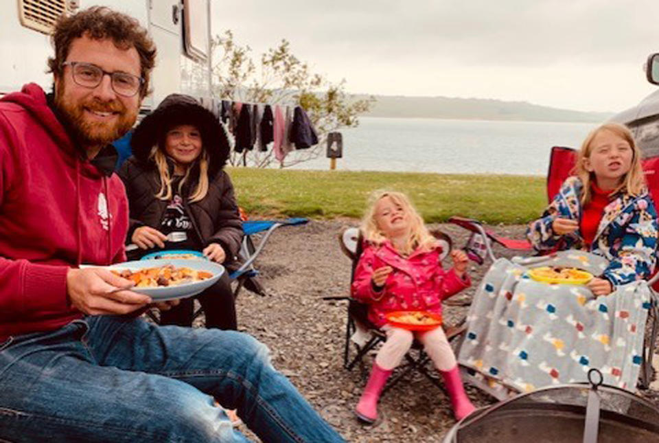 Ben and the girls enjoy family time around a campfire outside the caravan. (Caters)