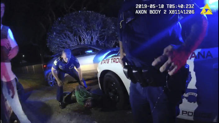 In this image from the body video camera of Louisiana State Police Lt. John Clary, Trooper Kory York stands over Ronald Greene, lying on his stomach, outside of Monroe, La., on May 10, 2019. Videos of the incident, obtained by The Associated Press, show Louisiana state troopers stunning, punching and dragging the Black man as he apologizes for leading them on a high-speed chase. (Louisiana State Police via AP)