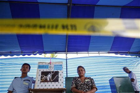 A man votes as officials sit by a ballot box at a polling station in Bangkok during a vote to elect a new Senate March 30, 2014. REUTERS/Damir Sagolj