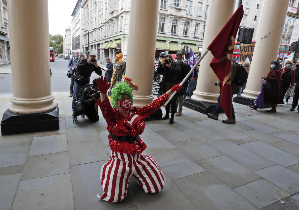 An actor dressed as a pantomime dame kneels in front of a theatre during a march on Parliament to demand more support for the theatre sector amid the COVID-19 pandemic in London, Wednesday, Sept. 30, 2020. (AP Photo/Frank Augstein)