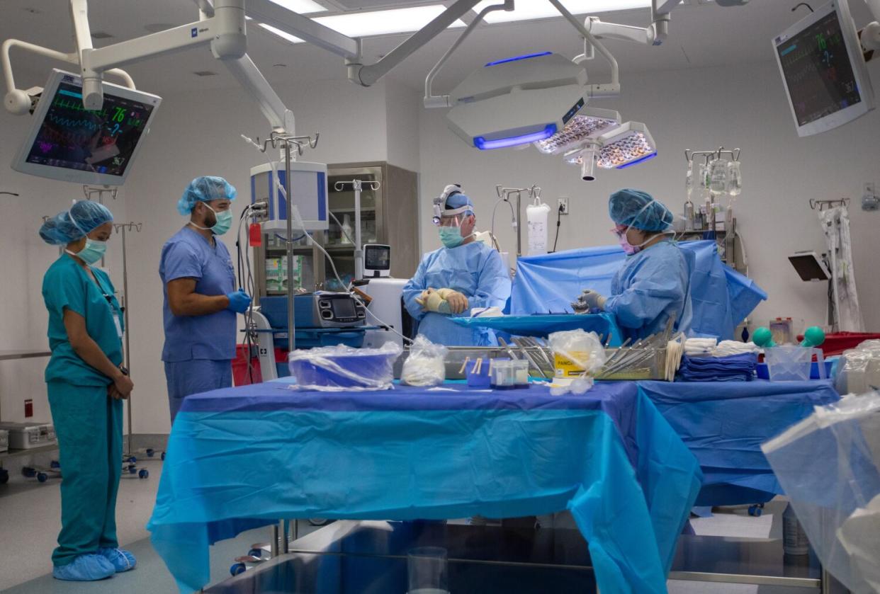 A surgical team stands around a covered operating table in an operating room