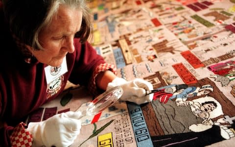 Volunteer conservator Tilly Trotter looks at the New World Tapestry - Credit: SWNS