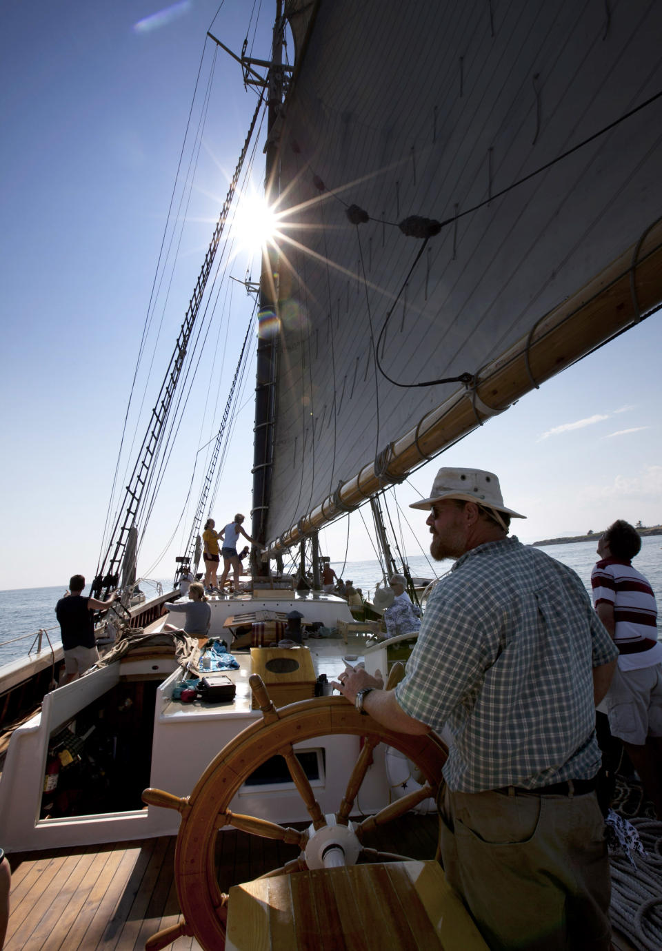 In this photo made Friday, August 3, 2012, Captain Barry King mans the helm of the schooner Mary Day on a three-day cruise on Penobscot Bay off Camden, Maine. The 90-foot Mary Day, which is celebrating its 50th season, is the first schooner in the Maine windjammer fleet to be built specifically to accommodate passengers. Its sleeping cabins are heated and have nine feet of headroom. (AP Photo/Robert F. Bukaty)