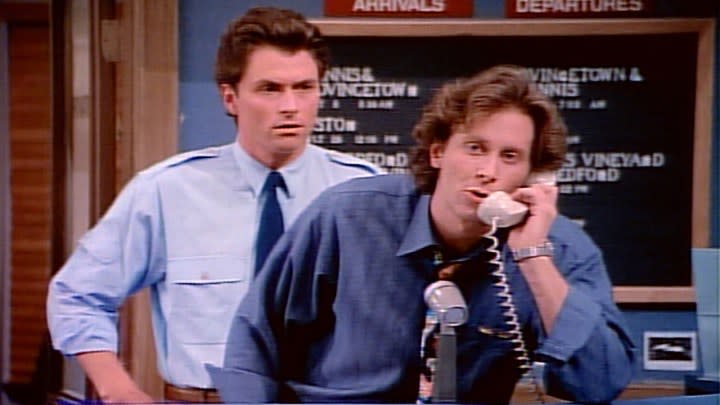 A man holding a landline phone, another behind him in a scene from Wings.