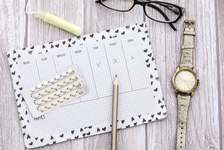 A calendar surrounded by EC pills, a watch, a pair of eyeglasses, and a tampon