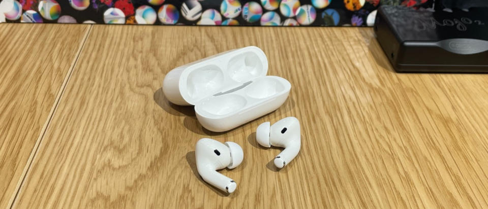 Apple AirPods Pro 1st gen with their charging case on a wooden table