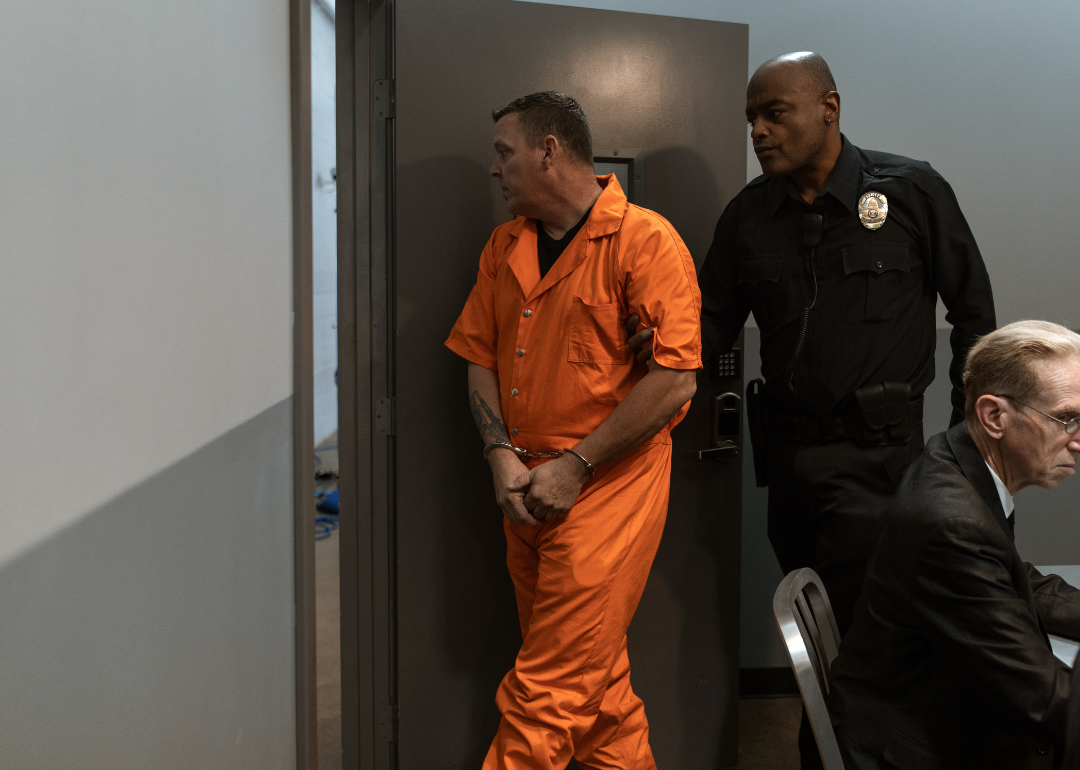 A correctional officer escorting a prisoner out of a room.