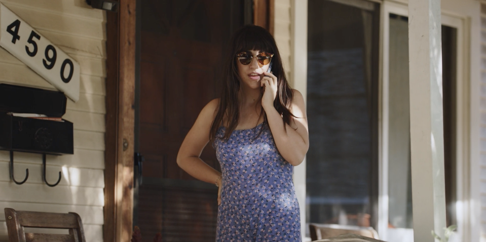 leah stands on the porch as she talks on the phone