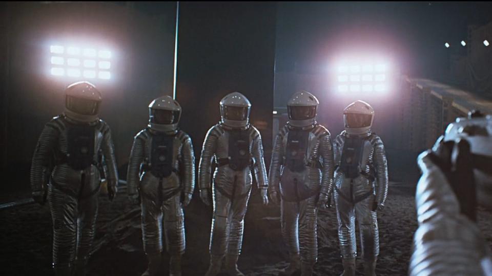men in spacesuits in front of monolith