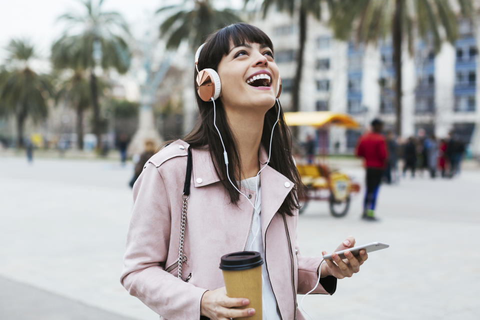 Woman drinking coffee while listening to her headphones.