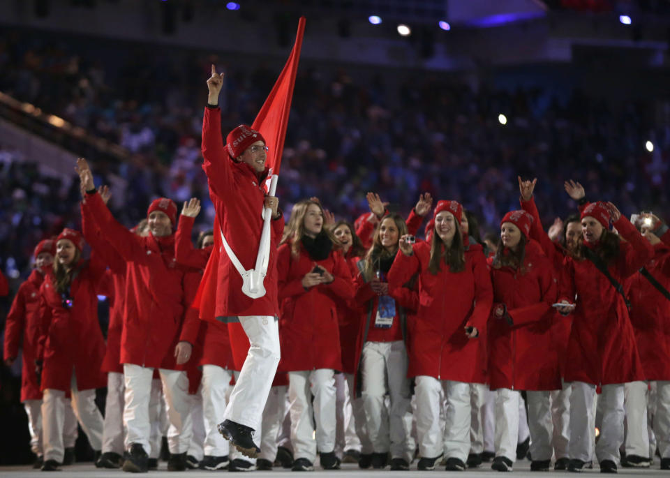 Simon Ammann of Switzerland carries the national flag as he leads his team into the stadium during the opening ceremony of the 2014 Winter Olympics in Sochi, Russia, Friday, Feb. 7, 2014. (AP Photo/Matt Dunham)
