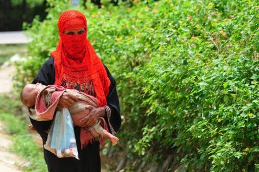 A Rohingya Muslim woman walks with her child at an unregistered refugee camp in Teknaf, Bangladesh in June 2012. Bangladesh has ordered three international charities to stop providing aid to Rohingya refugees who cross the border to flee persecution and violence in Myanmar, an official said Thursday