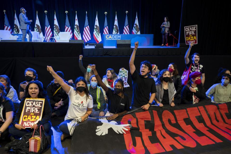 Demonstrators sit in front of a stage