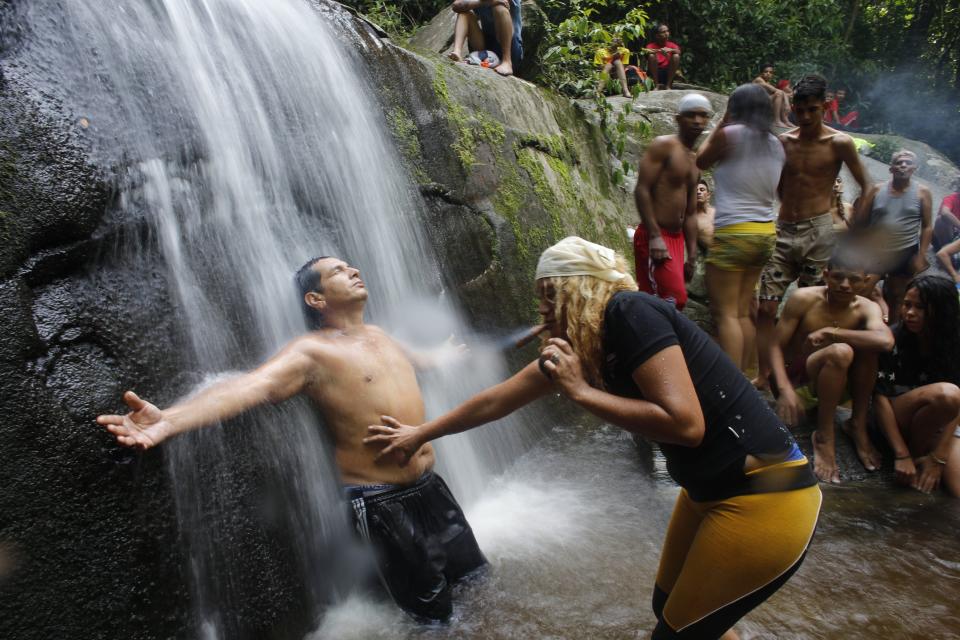 In this photo taken Oct. 12, 2019, a spiritual guide known as a "madrina" performs a ritual on a man training to become a medium to receive spirits into his body on Sorte Mountain where followers of indigenous goddess Maria Lionza gather annually in Venezuela's Yaracuy state. The tradition is hundreds of years old and draws on elements of the Afro-Caribbean religion Santeria and indigenous rituals, as well as Catholicism. (AP Photo/Ariana Cubillos)