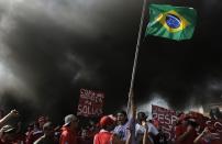 Members of Brazil's Homeless Workers' Movement (MTST), who are living at the "People's World Cup Camp" which houses some 2,800 families of the movement in the district of Itaquera near Sao Paulo's World Cup stadium, Arena de Sao Paulo, block a road during a protest against the 2014 World Cup in Sao Paulo, May 15, 2014. Cities across Brazil braced for demonstrations on Thursday, as disparate protest movements seek to criticize spending on the upcoming World Cup soccer tournament and revive a call for better public services that swept the country last June. Though most demonstrations are expected to gain steam later in the day, protestors in Sao Paulo, the country's biggest city, by early morning had blocked a major thoroughfare with burning tires and disrupted commutes elsewhere. REUTERS/Nacho Doce (BRAZIL - Tags: SPORT SOCCER WORLD CUP CIVIL UNREST)