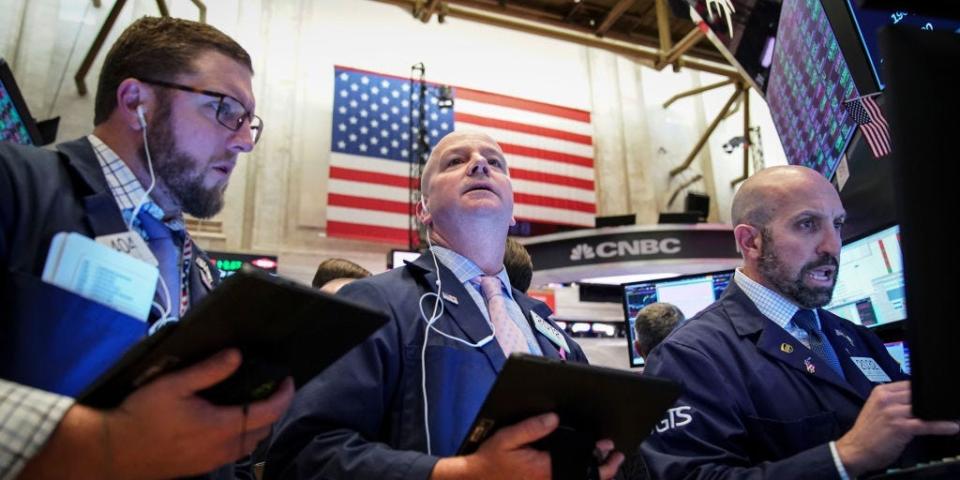 An American flag hangs behind traders working on the floor of the New York Stock Exchange (NYSE) on October 11, 2019 in New York City.