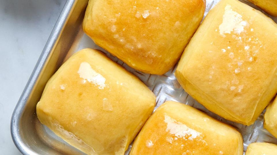 copycat texas roadhouse dinner rolls with flaky salt on a baking sheet cinnamon honey butter