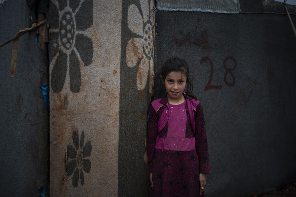 In this Thursday, March 12, 2020 photo, Yasmin poses for photo outside her tent at an informal camp for people displaced by fighting outside of Idlib city, Syria. Idlib city is the last urban area still under opposition control in Syria, located in a shrinking rebel enclave in the northwestern province of the same name. Syria’s civil war, which entered its 10th year Monday, March 15, 2020, has shrunk in geographical scope -- focusing on this corner of the country -- but the misery wreaked by the conflict has not diminished. (AP Photo/Felipe Dana)