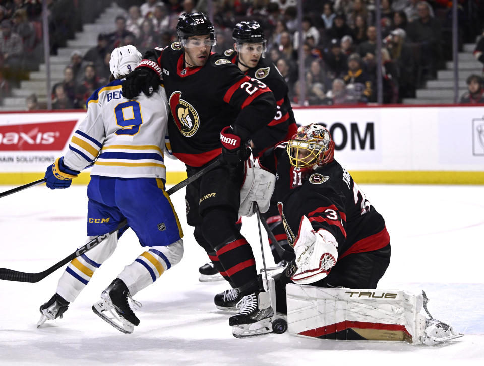 Ottawa Senators goaltender Anton Forsberg (31) makes a save in front of Senators defenseman Travis Hamonic (23) and Buffalo Sabres left wing Zach Benson (9) during first-period NHL hockey game action in Ottawa, Ontario, Sunday, Dec. 31, 2023. (Justin Tang/The Canadian Press via AP)