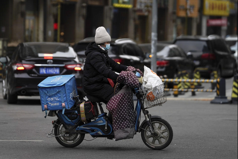 A food delivery worker wearing a face mask to help curb the spread of the coronavirus rides on a street in Beijing on Thursday, Jan. 14, 2021. The e-commerce workers and delivery people who kept China fed during the pandemic, making their billionaire bosses even richer, are so unhappy with their pay and treatment that one just set himself on fire in protest. (AP Photo/Andy Wong)