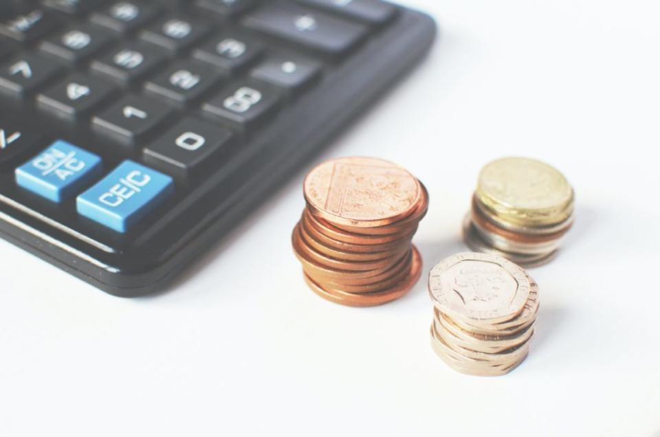 Three stacks of gold coins next to a calculator